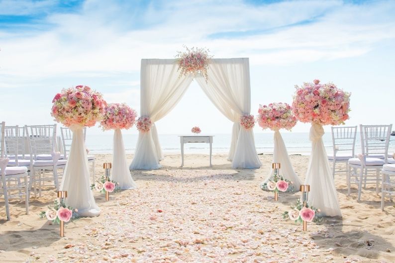 beach wedding with flowers on stake lights