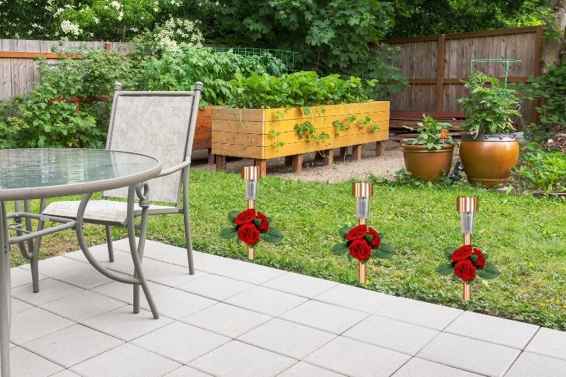 stake lights with red roses along patio