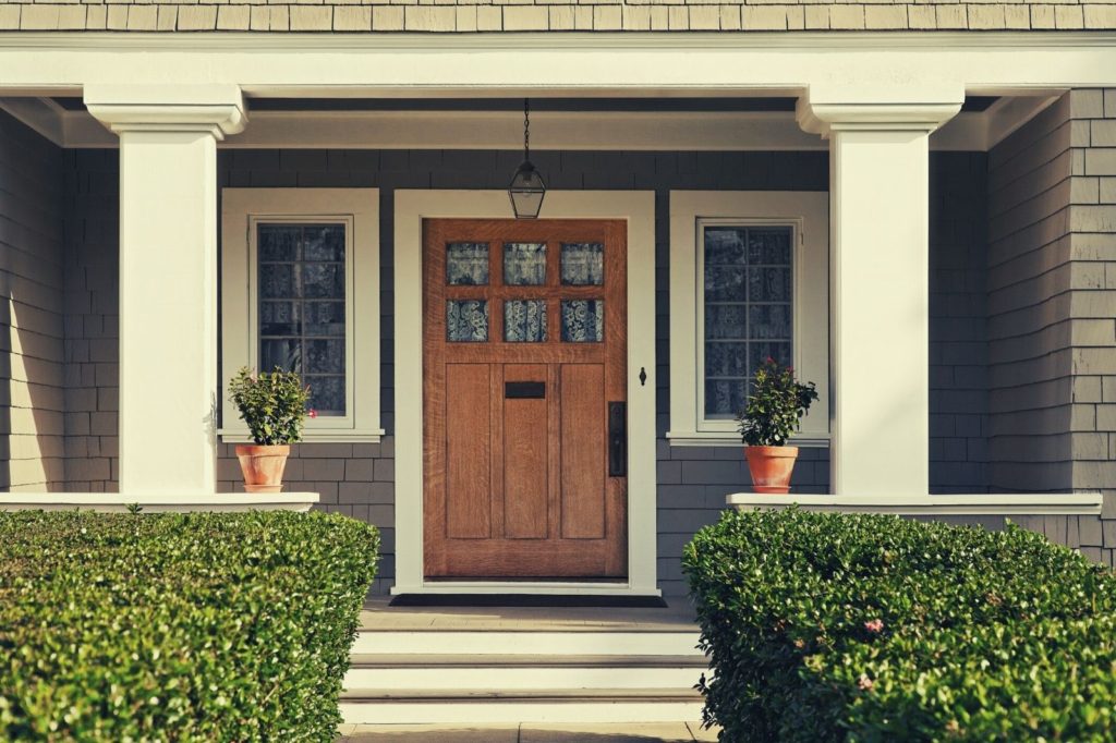 undecorated front porch with columns and shrubs